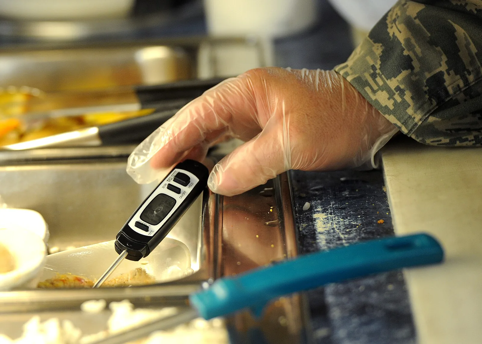 A food worker checks the temperature of food on a serving line. The picture is not from any kitchen named in this story.